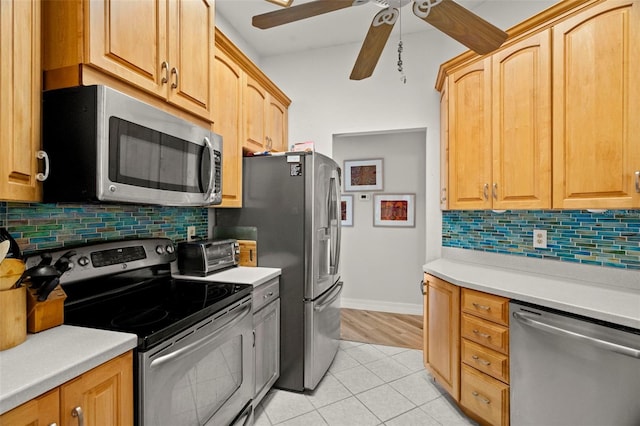 kitchen featuring appliances with stainless steel finishes, light tile patterned floors, ceiling fan, and decorative backsplash