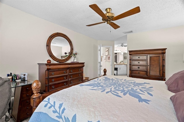 bedroom with ceiling fan, connected bathroom, and a textured ceiling