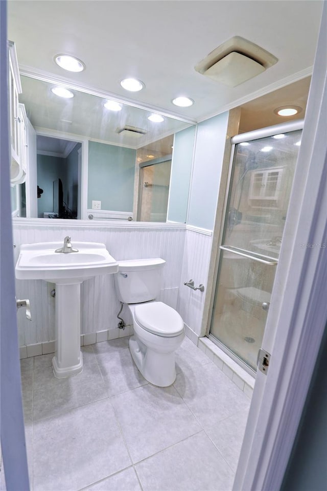 bathroom featuring tile patterned flooring, toilet, crown molding, and walk in shower