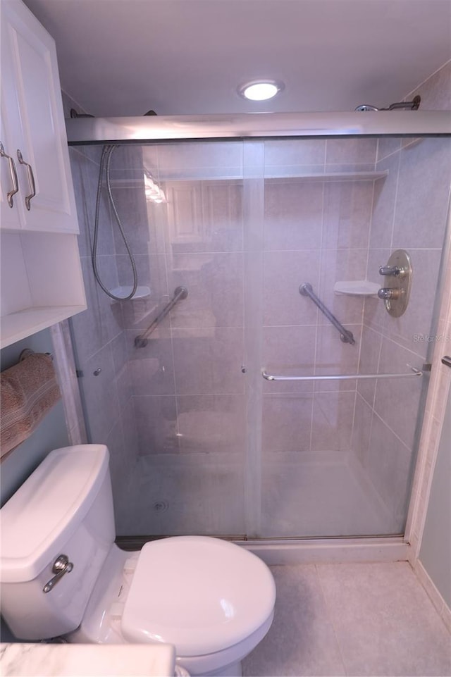 bathroom featuring walk in shower, tile patterned floors, and toilet