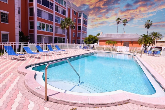 pool at dusk featuring a patio