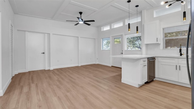 kitchen featuring decorative light fixtures, white cabinetry, sink, light hardwood / wood-style floors, and kitchen peninsula