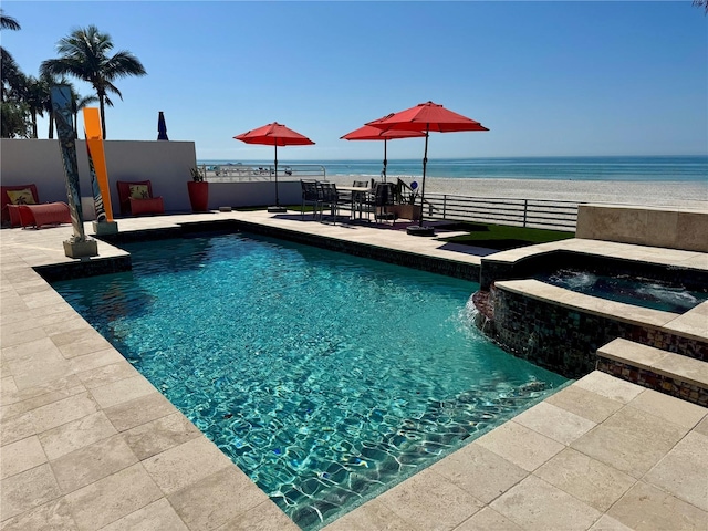 view of pool featuring a patio area, a water view, and an in ground hot tub