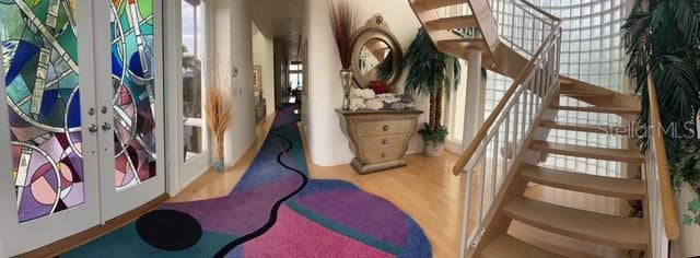 stairs with hardwood / wood-style flooring and french doors