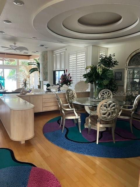 dining room featuring hardwood / wood-style flooring, a healthy amount of sunlight, and a tray ceiling