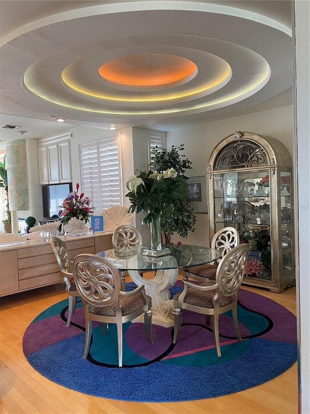 dining space featuring a raised ceiling and hardwood / wood-style floors