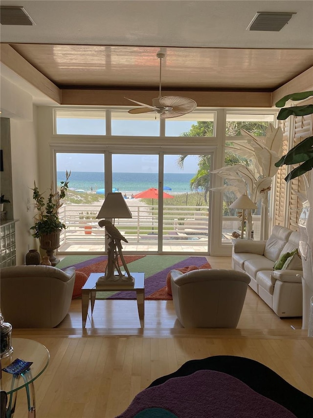 living room with light hardwood / wood-style flooring, ceiling fan, and a water view