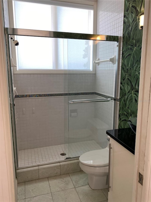 bathroom with tile patterned flooring, a shower with shower door, toilet, and a healthy amount of sunlight