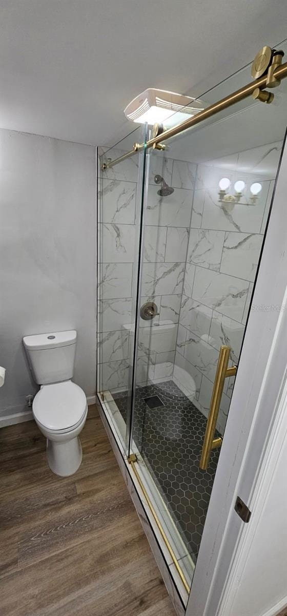 bathroom with hardwood / wood-style flooring, toilet, and an enclosed shower