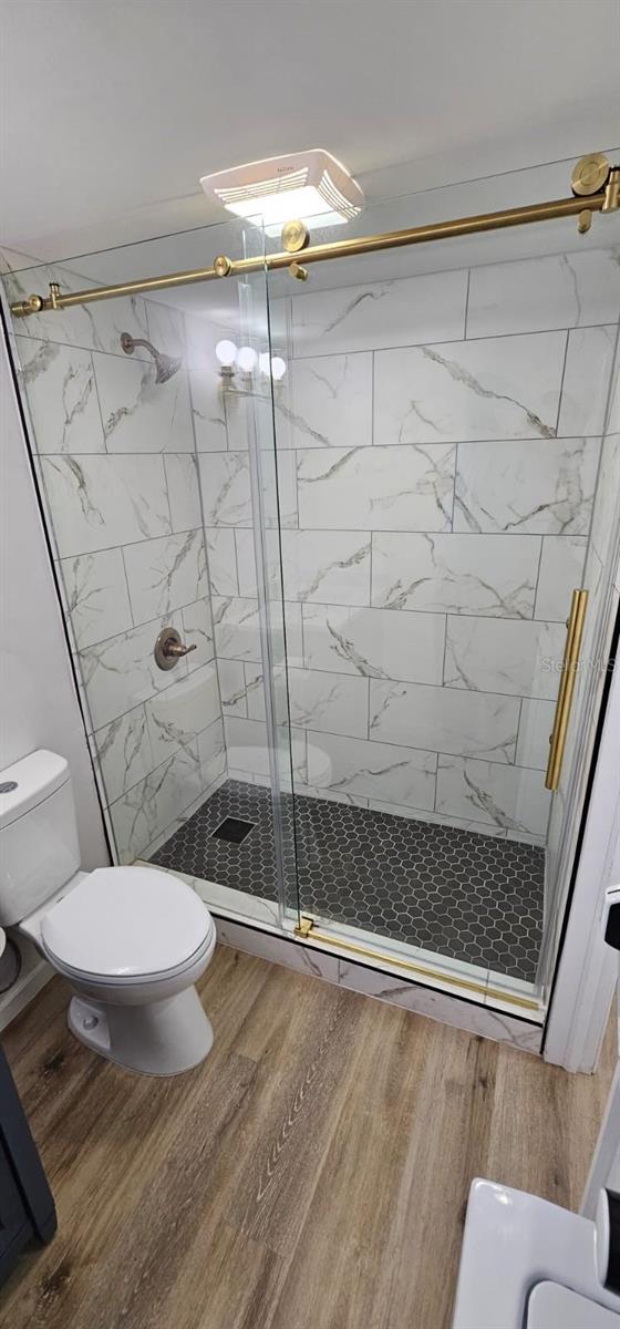 bathroom featuring toilet, hardwood / wood-style floors, and walk in shower