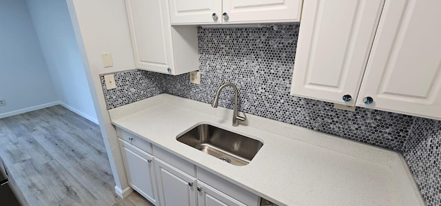 kitchen with sink, white cabinets, light stone counters, and decorative backsplash