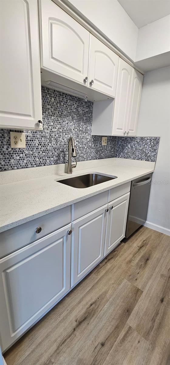 kitchen featuring white cabinetry, stainless steel dishwasher, sink, and tasteful backsplash