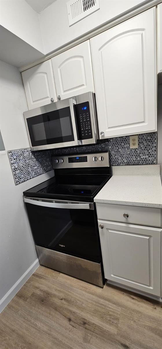 kitchen featuring white cabinetry, tasteful backsplash, appliances with stainless steel finishes, and light hardwood / wood-style flooring