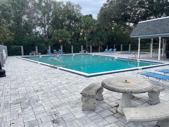 view of swimming pool featuring a patio area and a hot tub