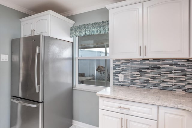 kitchen with stainless steel refrigerator, ornamental molding, tasteful backsplash, and white cabinets