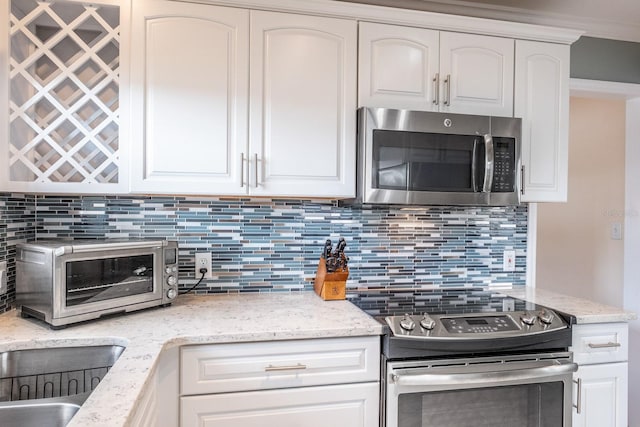 kitchen with white cabinetry, light stone counters, decorative backsplash, and appliances with stainless steel finishes