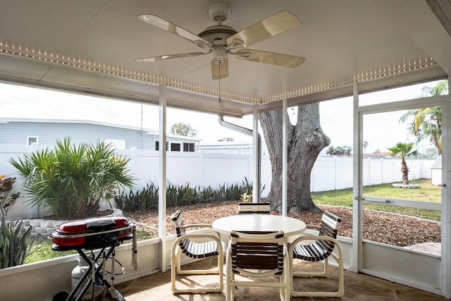 sunroom / solarium with ceiling fan and a water view