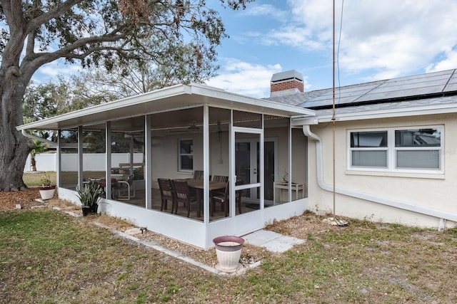 exterior space featuring a yard, a sunroom, and solar panels