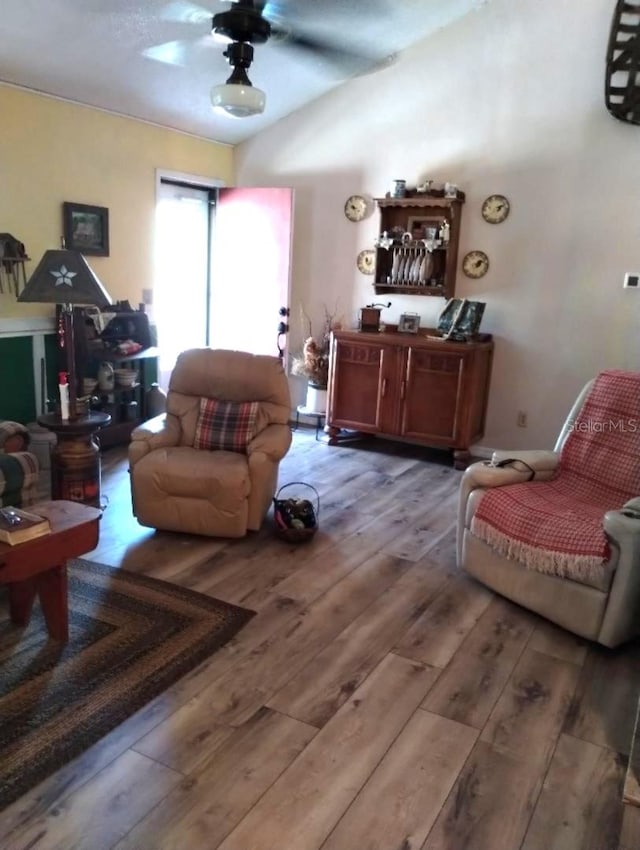 living room with lofted ceiling, hardwood / wood-style flooring, and ceiling fan