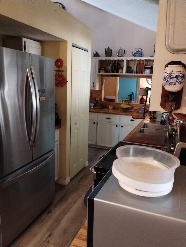 kitchen featuring light hardwood / wood-style floors, stainless steel refrigerator, and white cabinets