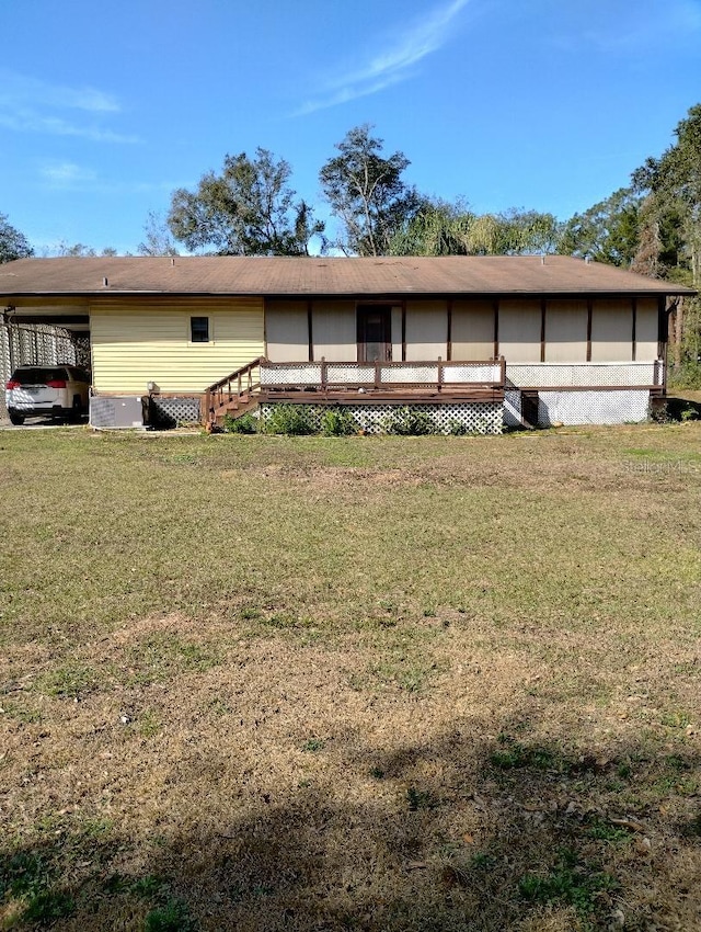 view of front of property featuring a wooden deck, a carport, and a front yard