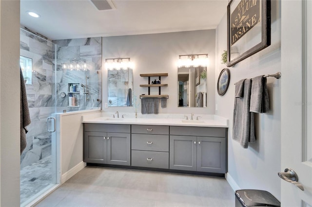 full bathroom with double vanity, a stall shower, visible vents, and a sink