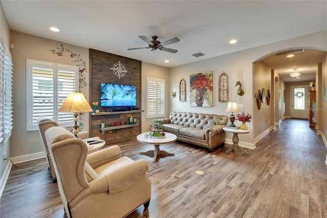 living room featuring arched walkways, wood finished floors, a wealth of natural light, and recessed lighting