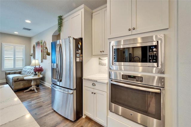 kitchen featuring white cabinets, light stone countertops, visible vents, and stainless steel appliances