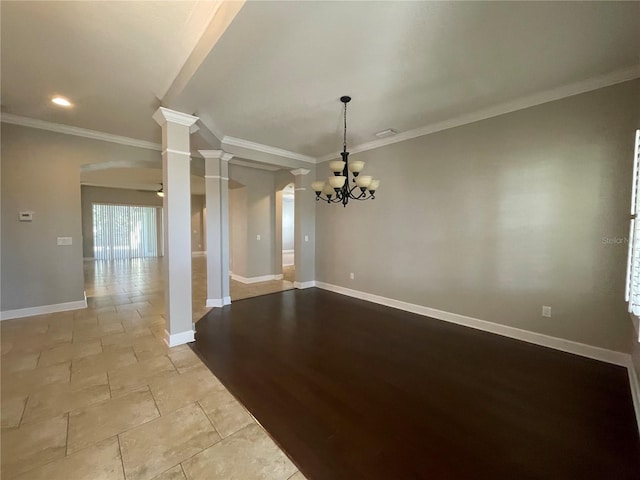 empty room with decorative columns, ornamental molding, and a chandelier