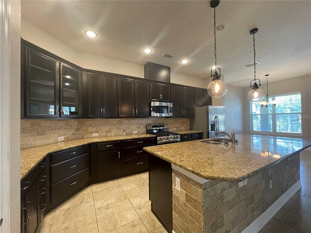 kitchen featuring light stone counters, stainless steel appliances, sink, and an island with sink