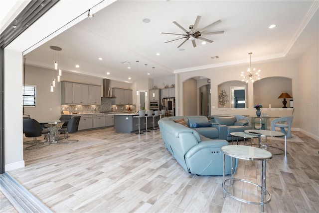 living room with ornamental molding, ceiling fan with notable chandelier, and light hardwood / wood-style flooring