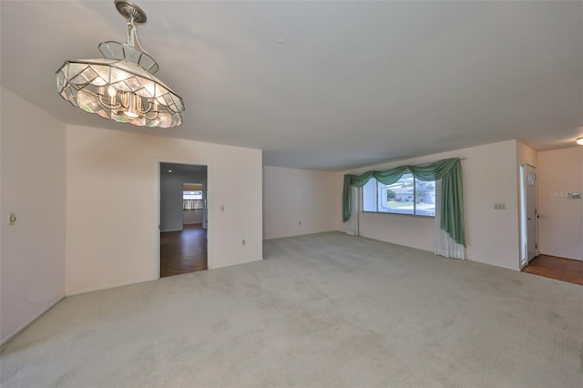 unfurnished living room with a notable chandelier and carpet flooring