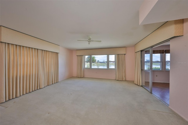 carpeted spare room featuring a water view and ceiling fan