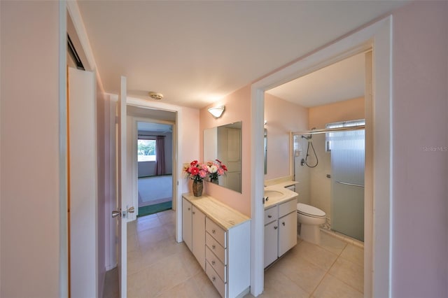 bathroom with vanity, a shower with shower door, tile patterned floors, and toilet