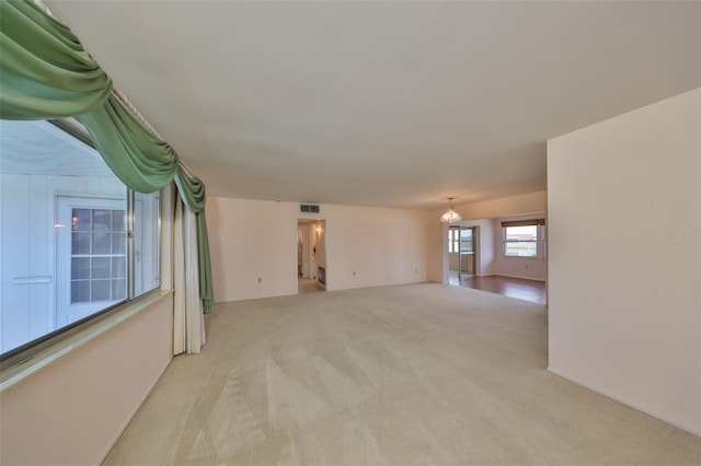 carpeted spare room featuring a chandelier