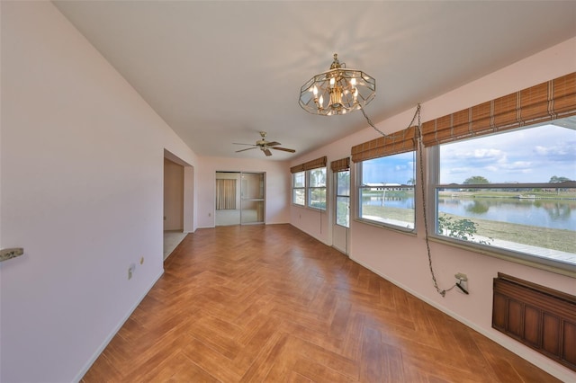 unfurnished room with a water view, parquet floors, and ceiling fan with notable chandelier