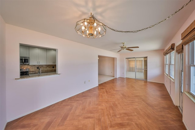 unfurnished room featuring light parquet flooring and ceiling fan with notable chandelier