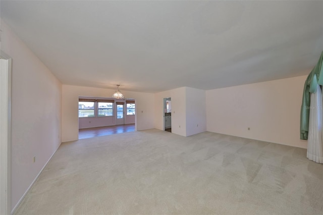 unfurnished living room featuring an inviting chandelier and light colored carpet