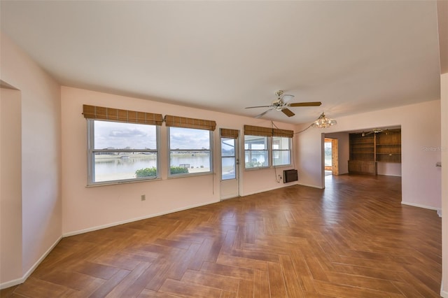 empty room with parquet flooring, an AC wall unit, ceiling fan, and a water view