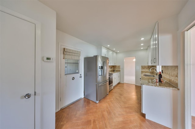 kitchen featuring light parquet floors, appliances with stainless steel finishes, sink, and white cabinets