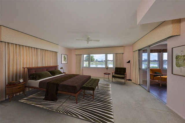 bedroom featuring a water view, light colored carpet, and ceiling fan