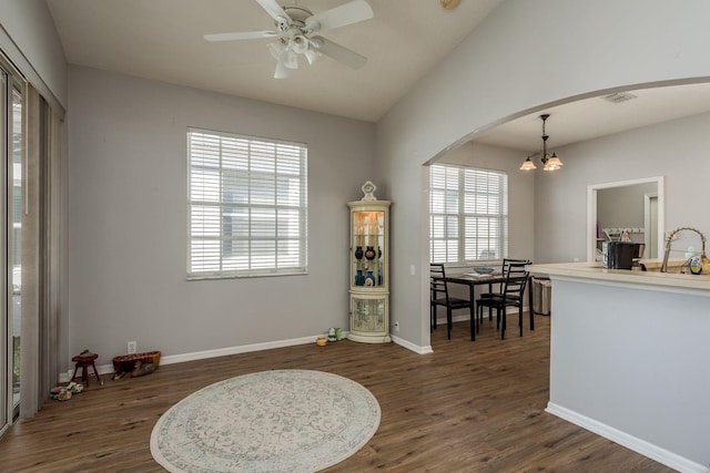 interior space featuring arched walkways, dark wood-style flooring, lofted ceiling, and baseboards