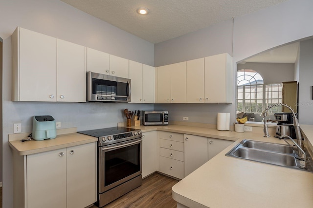 kitchen featuring a textured ceiling, appliances with stainless steel finishes, light countertops, and a sink