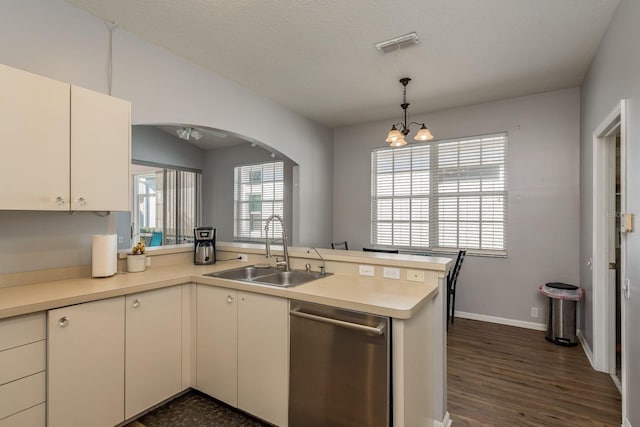 kitchen featuring dishwasher, decorative light fixtures, a peninsula, light countertops, and a sink