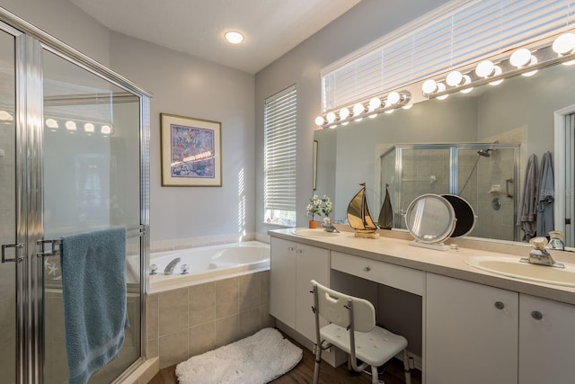 bathroom with a garden tub, double vanity, a stall shower, and a sink