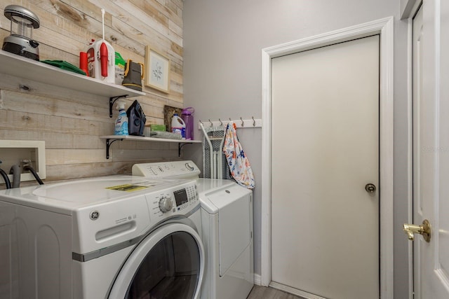 laundry area featuring laundry area, wooden walls, and washing machine and clothes dryer