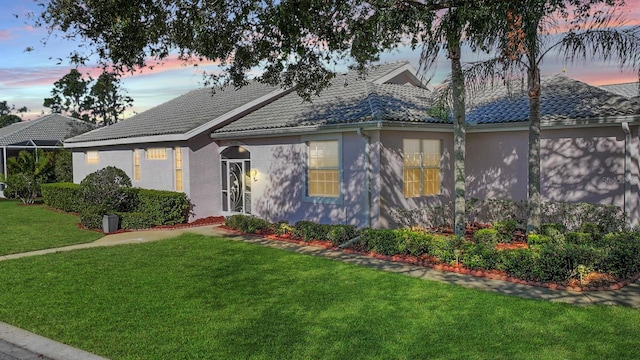 view of front of property featuring a tiled roof, a front lawn, and stucco siding