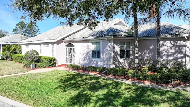 view of front of home with a tiled roof, a front lawn, and stucco siding