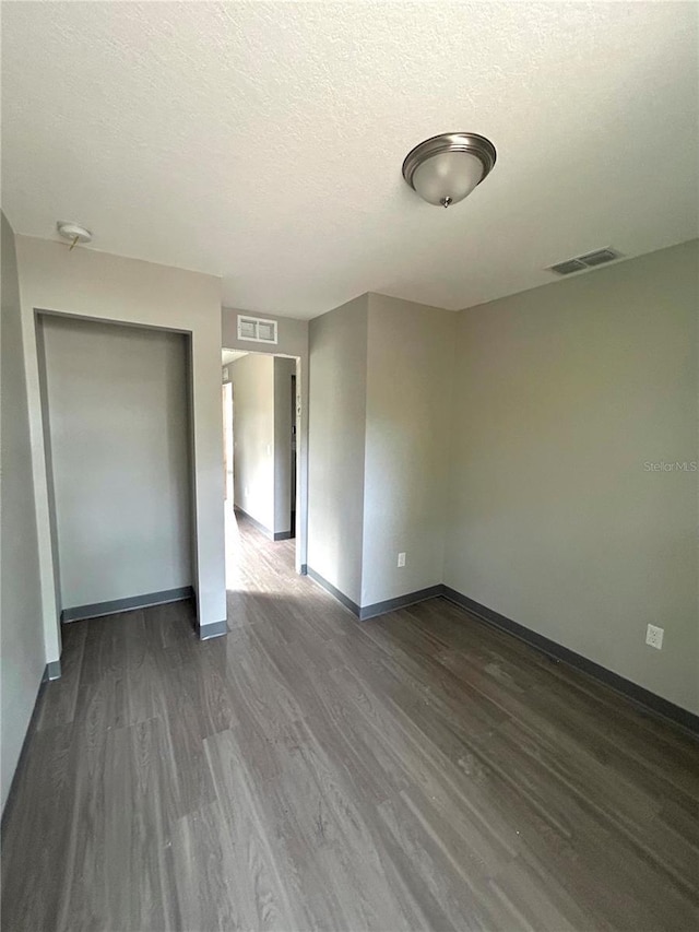 empty room featuring dark hardwood / wood-style floors and a textured ceiling