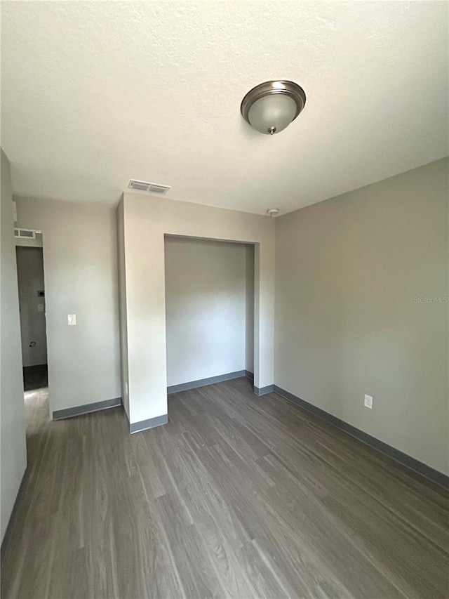 unfurnished bedroom with a closet, dark hardwood / wood-style floors, and a textured ceiling